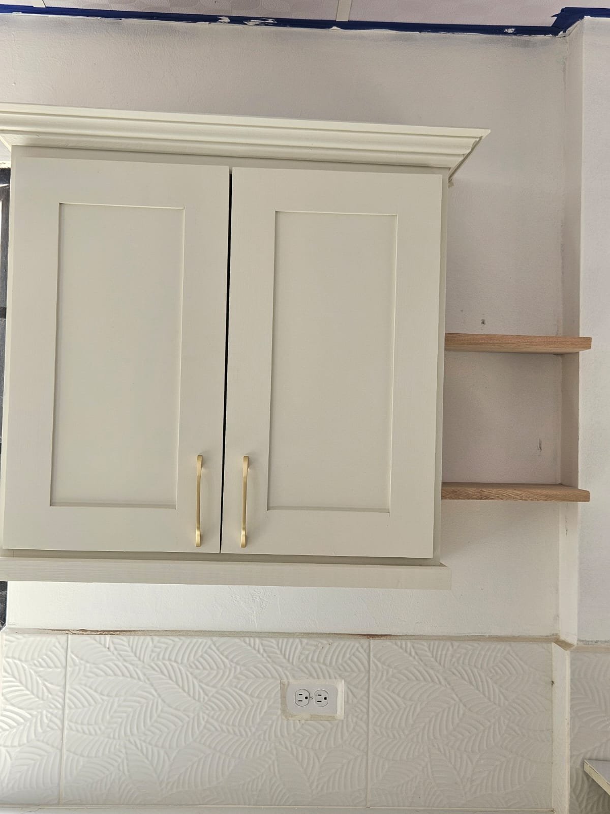 Cream shaker wall cabinet with brass handles and open wood shelves