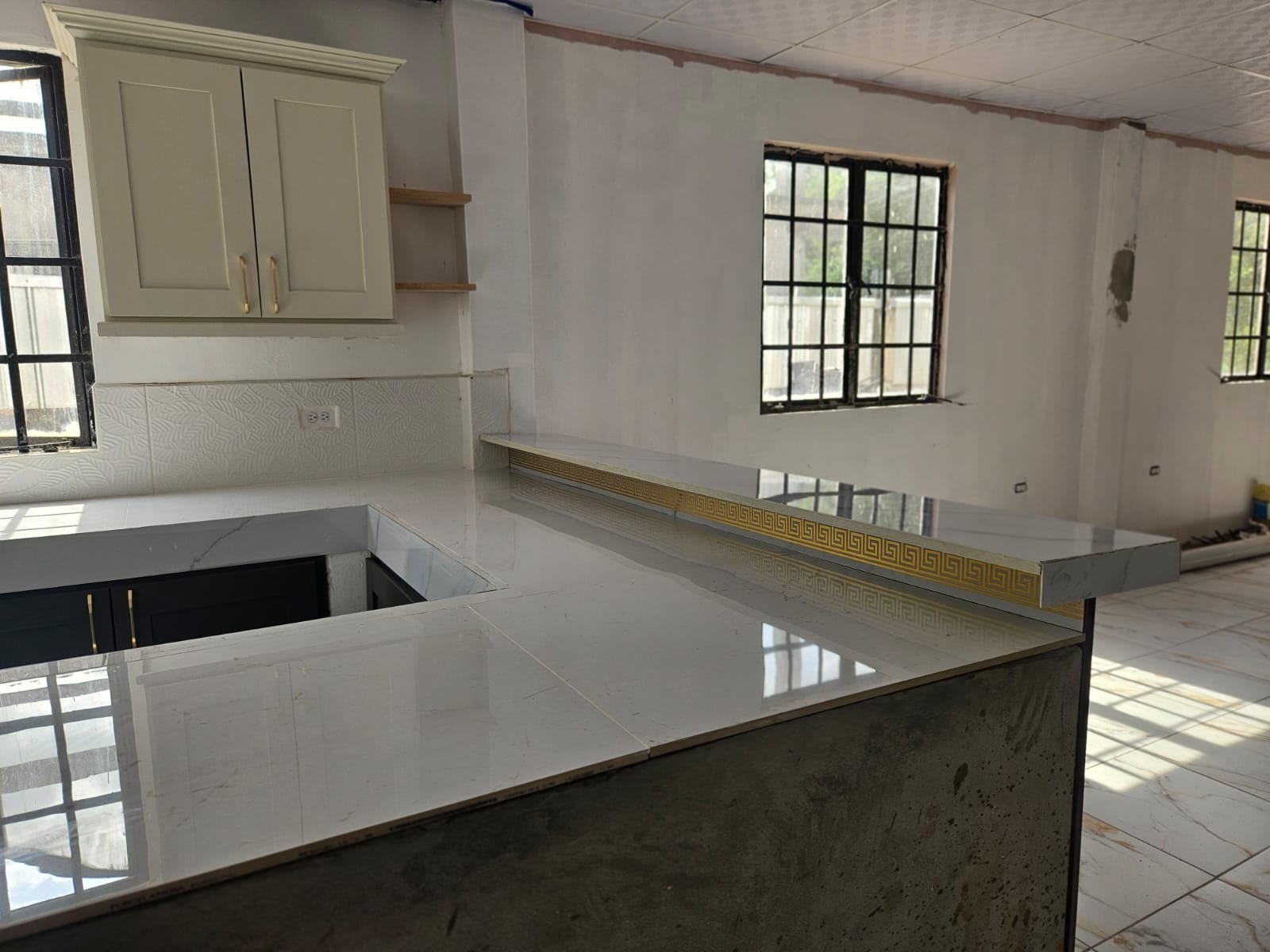 Custom kitchen countertop and breakfast bar with polished stone-look surfaces and cream upper cabinets