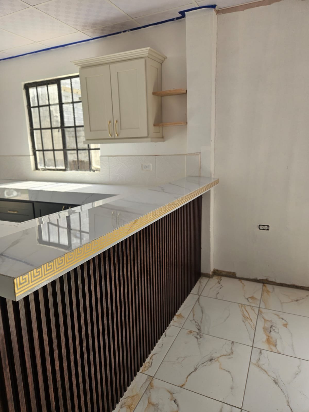 Kitchen island detail with stone-look countertop and vertical slatted breakfast bar front