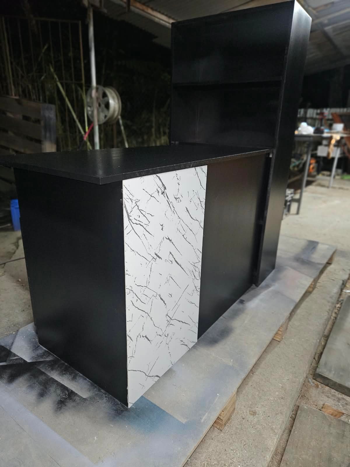 Black office desk build with marble-look feature panel photographed in the workshop